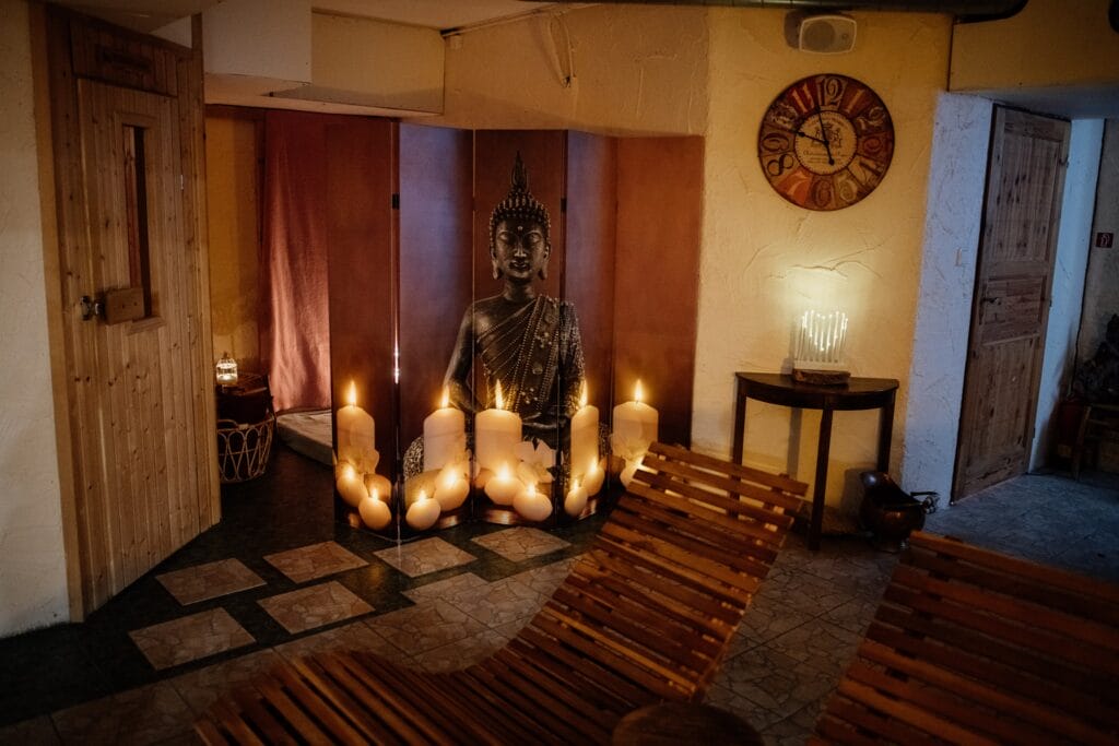 Wellness centrum s miestnosťou so sviečkami a sochou Budhu.