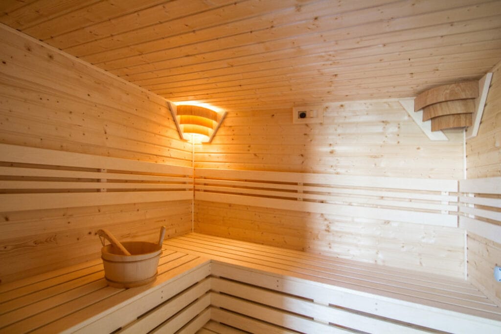 Drevená sauna s drevenou lavicou a vedrom, ktorá sa nachádza vo Wellness v hoteli Dobrá Lipa Vajnory.