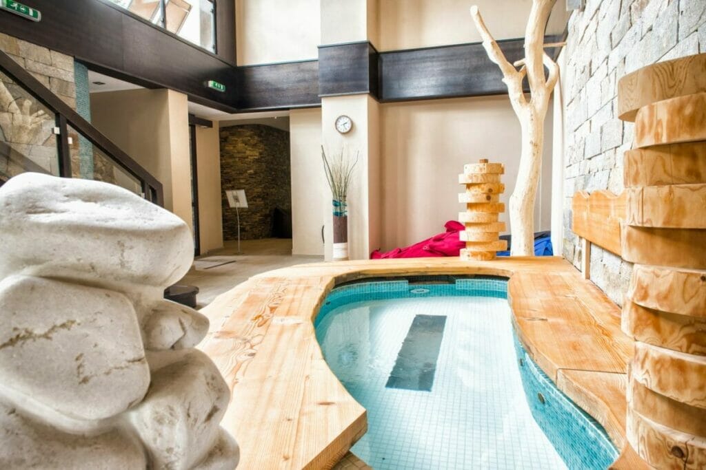 Wellness hotel s krytým bazénom a kamennými sochami.