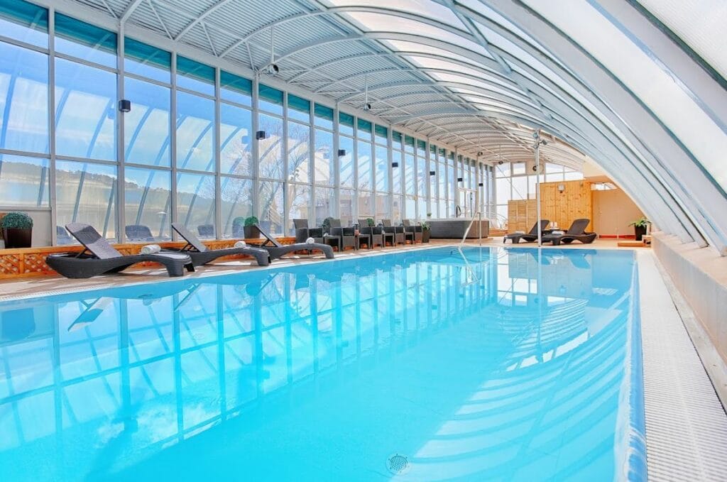 Veľký krytý bazén s ležadlami vo wellness centre v hoteli Magnólia Piešťany.