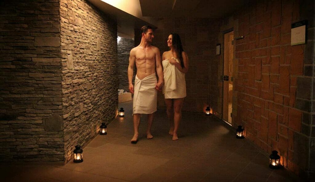 Muž a žena stojaci na chodbe so sviečkami vo Wellness centre 4 Elements.