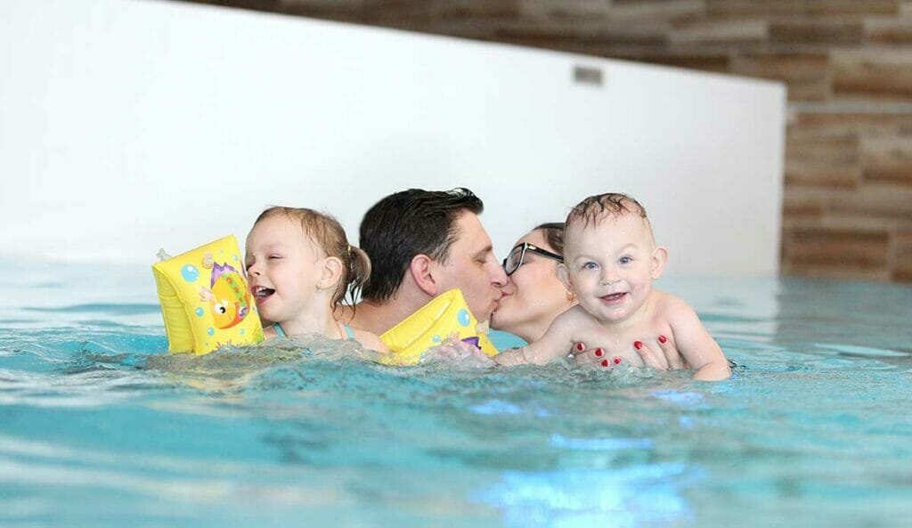 Rodina s malými deťmi vo wellness centre na krytej plavárni.
