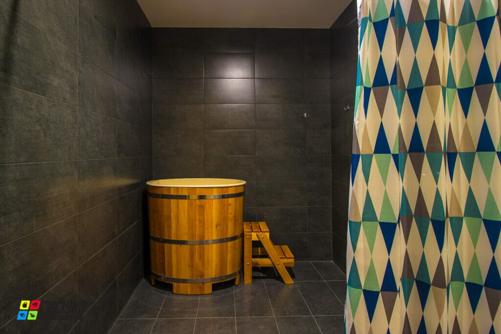 Fitness sauna v Poprade s dreveným sudom a sprchovacím závesom.