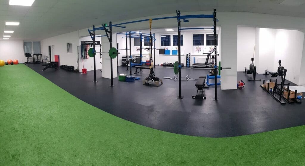 Fitness centrum so zeleným kobercom a vybavením v Banskej Bystrici.