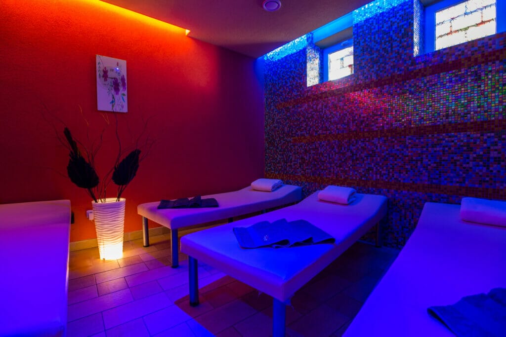 Relaxačné centrum FitHouse Spišská Nová Ves ponúka dve masážne lôžka v miestnosti s ambientným červeným a modrým svetlom.
