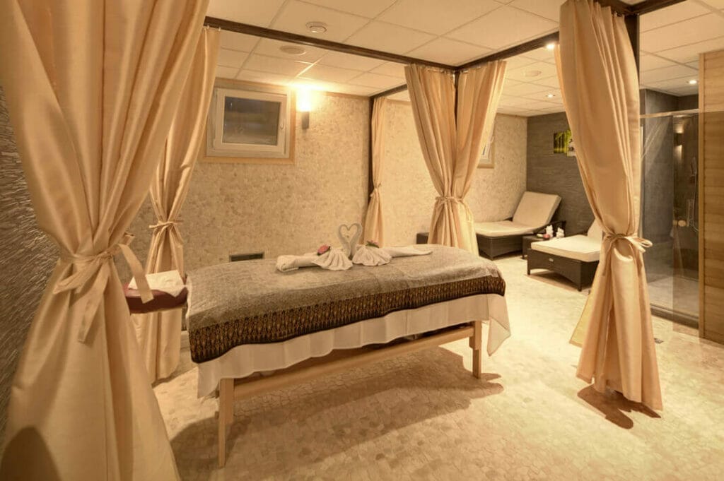 Kúpeľná miestnosť s masážnym stolom Nuad Thai a závesmi.