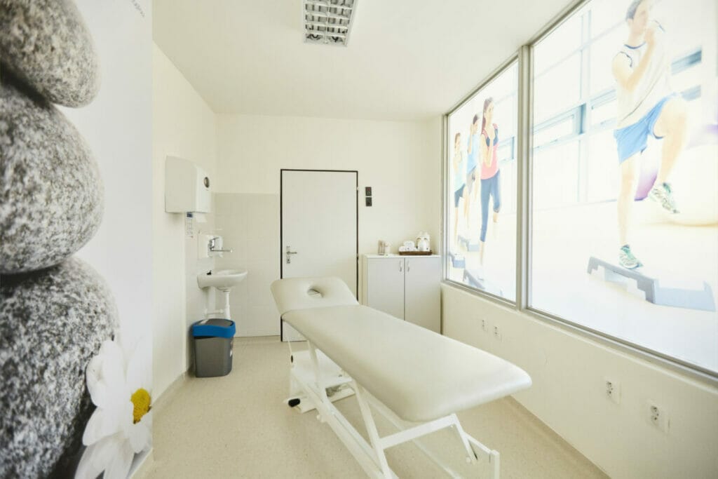 Miestnosť s masážnym stolom a oknom na Fyziatricko-rehabilitačnom oddelení Procare Vranov nad Topľou.