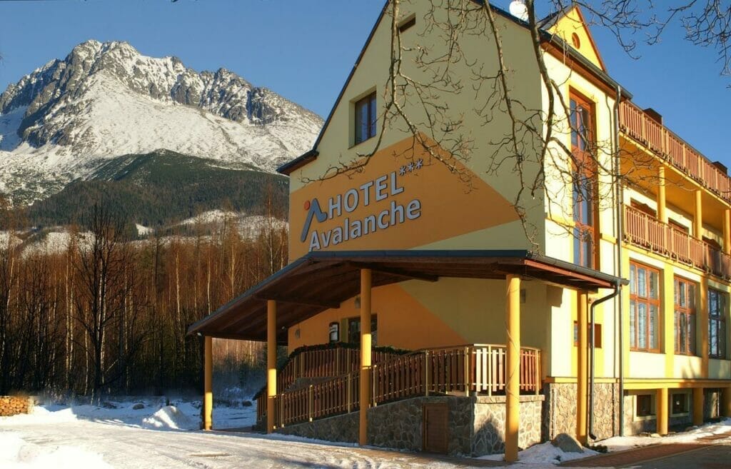 Wellness centrum v hoteli Avalanche Štôla, situované pri žltej budove s majestátnou horou v pozadí.