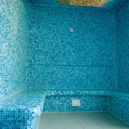 Wellness kúpeľňa s modrými obkladačkami a lavicou.