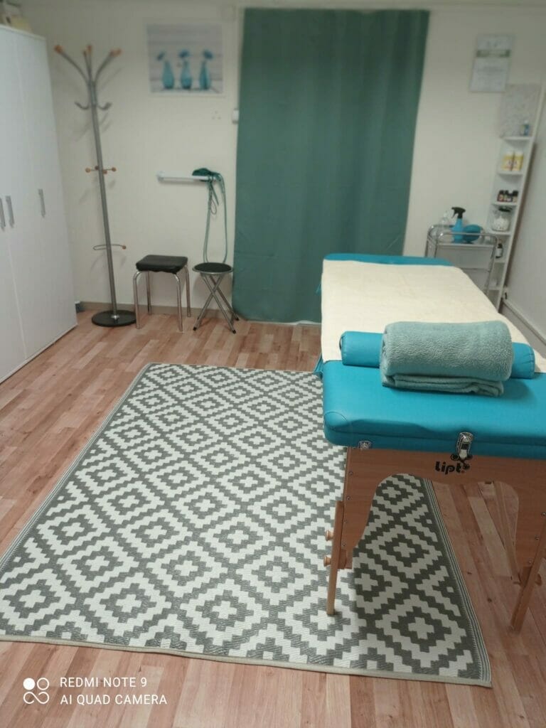 Miestnosť s masážnym stolom a modrým kobercom pre Masáže B&M Vranov nad Topľou.