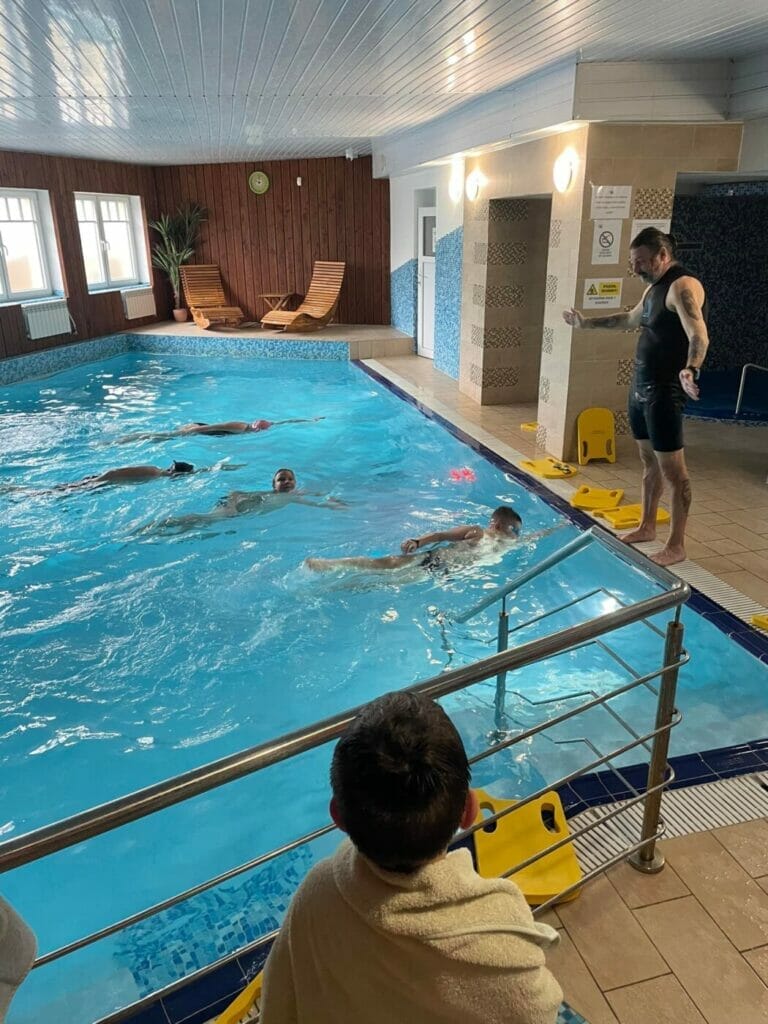 Skupina ľudí propagujúcich wellness a fitness v krytej plavárni s pomocou Aquabely.